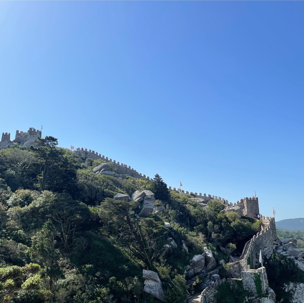 A castle atop a green hill under a clear sky
